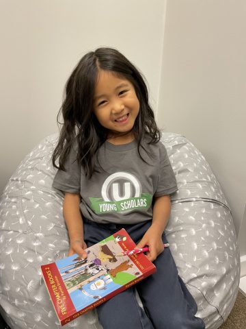 One of the youngest scholars in the program, kindergartener Karis Im, sits in the reading corner with her book. 